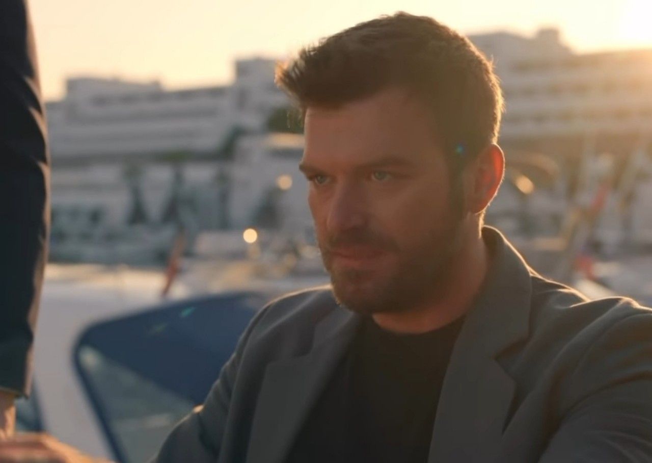 Kıvanç Tatlıtuğ, marinada gün batımında ceketle oturuyor. Kıvanç Tatlıtuğ, marinada gün batımında ceketle oturuyor.