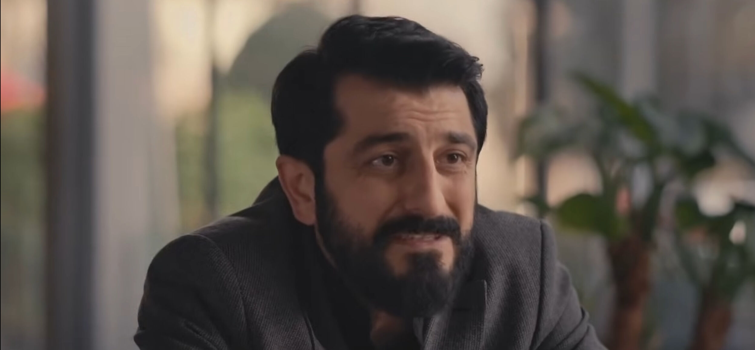 İç mekanda, takım elbiseli bir karakter masa başında oturuyor; arka planda büyük bir pencere ve yeşil bitkiler görülüyor. İç mekanda, takım elbiseli bir karakter masa başında oturuyor; arka planda büyük bir pencere ve yeşil bitkiler görülüyor.